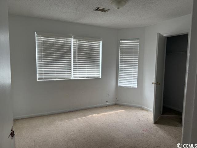 unfurnished bedroom featuring visible vents, a textured ceiling, baseboards, and carpet