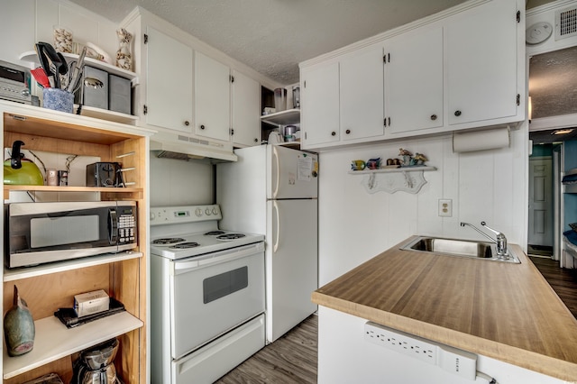 kitchen with open shelves, a sink, under cabinet range hood, dark wood finished floors, and white appliances