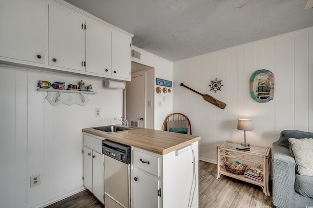 kitchen with a sink, visible vents, a textured ceiling, dishwasher, and wood finished floors