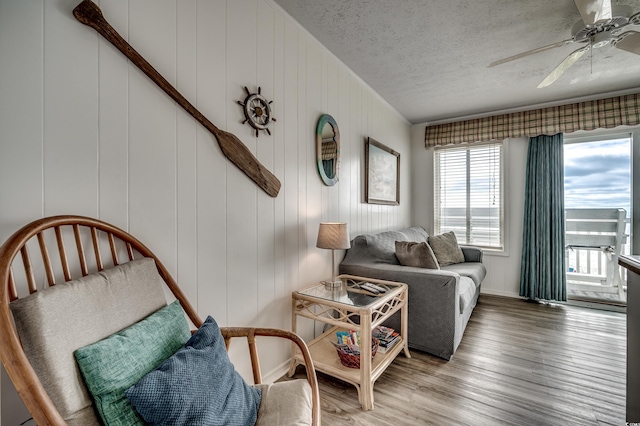 interior space with a textured ceiling, wood finished floors, ceiling fan, and baseboards