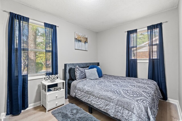 bedroom featuring a textured ceiling and light hardwood / wood-style flooring