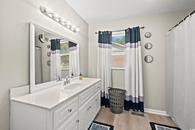 bathroom with a textured ceiling, wood-type flooring, vanity, and a wealth of natural light