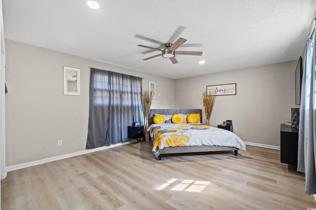 bedroom featuring light hardwood / wood-style floors, ceiling fan, and a textured ceiling