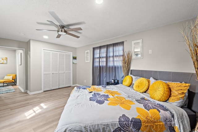 bedroom with a closet, ceiling fan, light wood-type flooring, and a textured ceiling