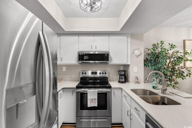 kitchen featuring sink, appliances with stainless steel finishes, white cabinets, and decorative backsplash