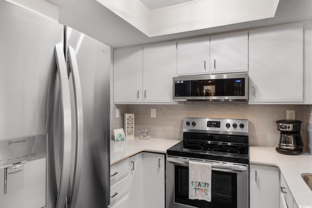 kitchen with white cabinetry, stainless steel appliances, and tasteful backsplash