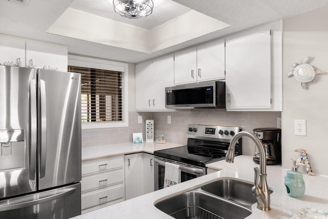 kitchen featuring appliances with stainless steel finishes, white cabinetry, and a raised ceiling