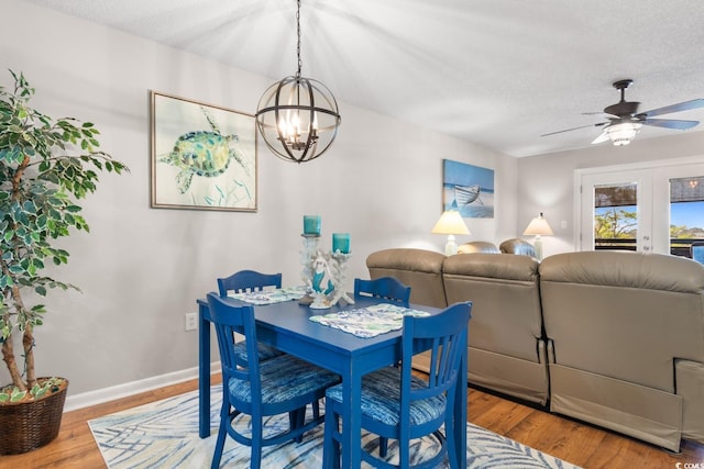 dining area with a textured ceiling, ceiling fan with notable chandelier, and hardwood / wood-style flooring