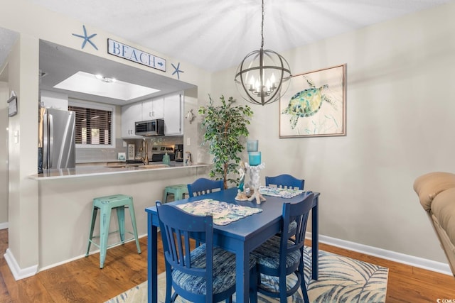 dining area featuring hardwood / wood-style flooring, sink, and a notable chandelier