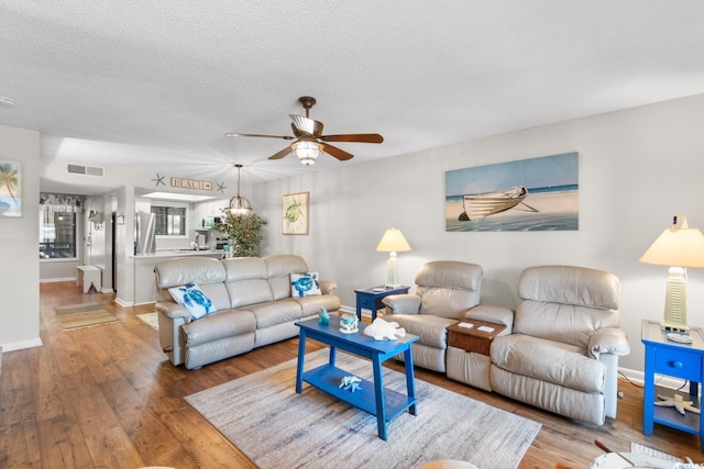 living room with a textured ceiling, ceiling fan, and hardwood / wood-style flooring