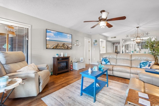 living room with a textured ceiling, hardwood / wood-style floors, and ceiling fan with notable chandelier