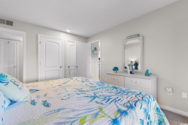 bedroom featuring a textured ceiling, carpet, and two closets