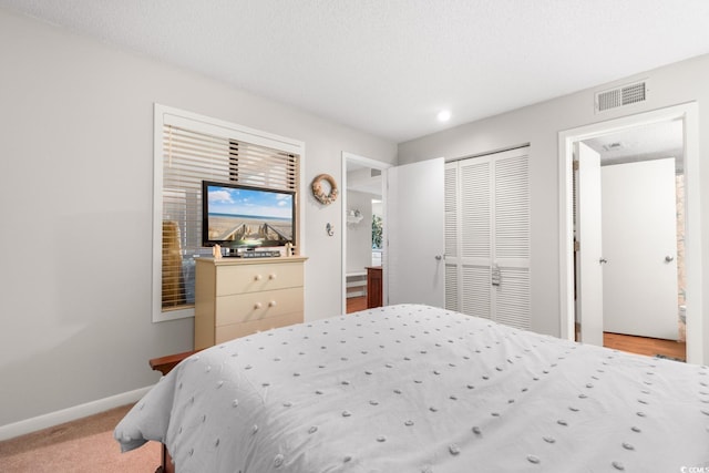 carpeted bedroom featuring a textured ceiling and a closet