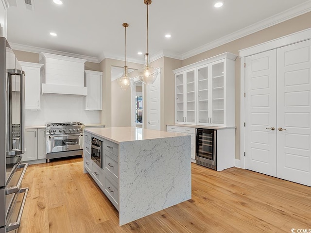 kitchen featuring light wood finished floors, beverage cooler, high end appliances, and crown molding