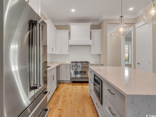 kitchen with high end appliances, light wood-style flooring, crown molding, premium range hood, and pendant lighting