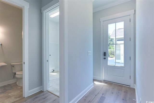 doorway with ornamental molding and light hardwood / wood-style floors