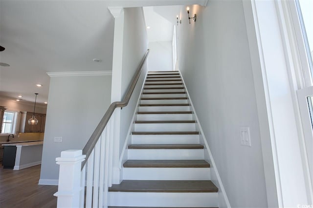 stairway featuring hardwood / wood-style floors, sink, and ornamental molding