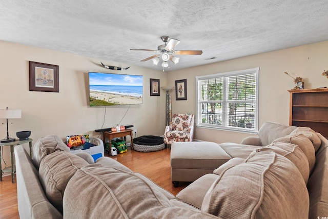 living room with ceiling fan, wood-type flooring, and a textured ceiling