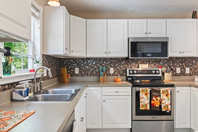 kitchen with stainless steel appliances, sink, white cabinetry, and tasteful backsplash