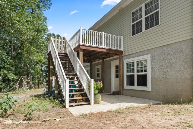 back of house with a playground and a deck