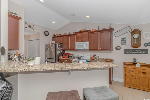 kitchen featuring light tile patterned floors, vaulted ceiling, white appliances, kitchen peninsula, and a breakfast bar