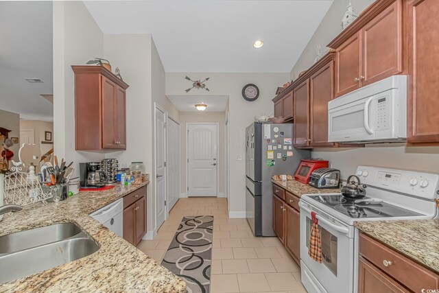 kitchen featuring light tile patterned floors, white appliances, sink, and light stone countertops