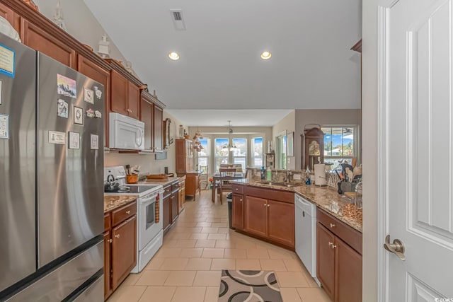 kitchen with a healthy amount of sunlight, sink, light tile patterned floors, and white appliances