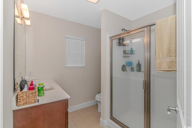 bathroom featuring tile patterned floors, a shower with shower door, toilet, and vanity