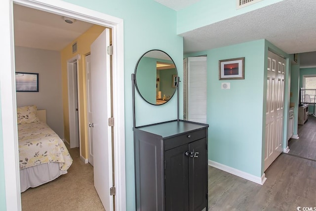 corridor with hardwood / wood-style flooring and a textured ceiling