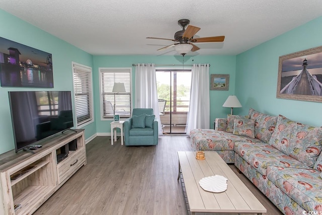 living room featuring light hardwood / wood-style floors, ceiling fan, and a textured ceiling