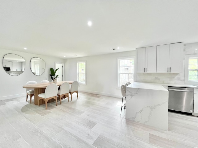 kitchen with white cabinetry, plenty of natural light, stainless steel dishwasher, and decorative backsplash