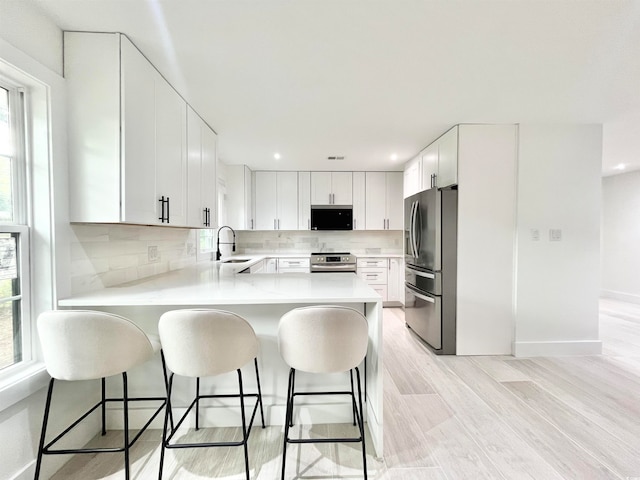 kitchen featuring white cabinets, plenty of natural light, stainless steel appliances, and kitchen peninsula