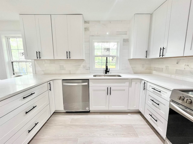 kitchen featuring a wealth of natural light, sink, appliances with stainless steel finishes, and white cabinetry