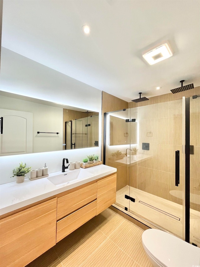 bathroom featuring tile patterned flooring, vanity, toilet, and a shower with shower door