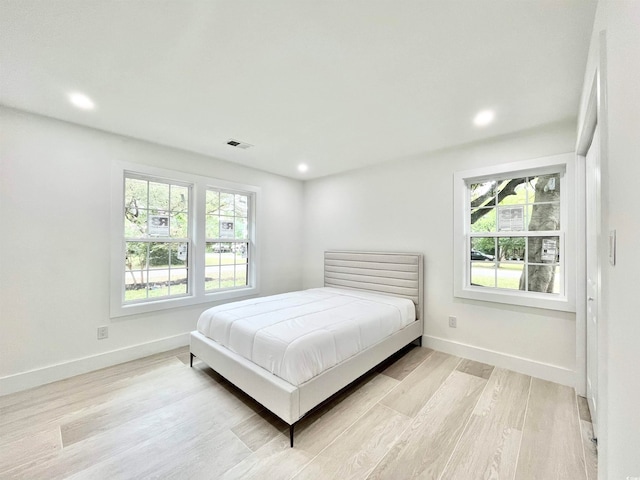 bedroom featuring multiple windows and light hardwood / wood-style flooring