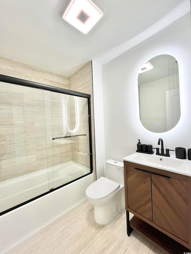 full bathroom featuring toilet, hardwood / wood-style flooring, bath / shower combo with glass door, and vanity