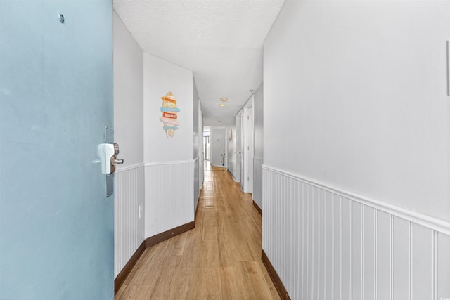 hallway featuring a textured ceiling and light hardwood / wood-style flooring