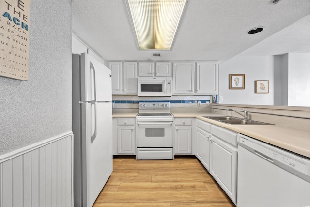 kitchen featuring light hardwood / wood-style flooring, white appliances, white cabinetry, sink, and a textured ceiling