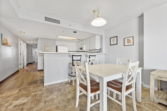 dining room with a textured ceiling and light hardwood / wood-style flooring