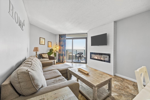 living room with a textured ceiling, a large fireplace, and a wall of windows