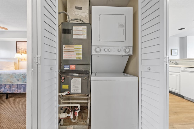 laundry area featuring light hardwood / wood-style flooring, stacked washer / drying machine, and sink