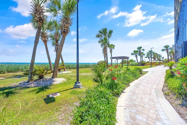 surrounding community with a pergola, a lawn, and a water view