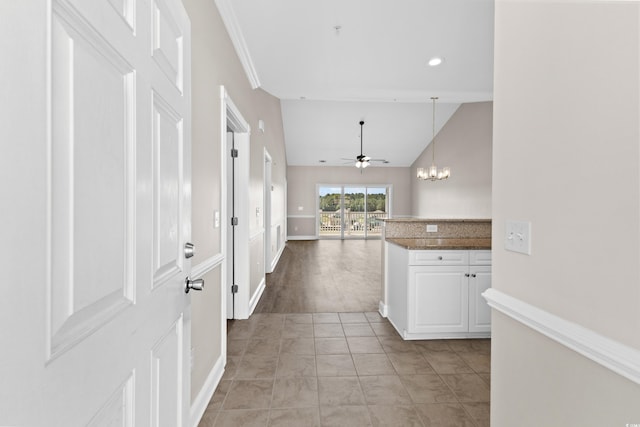 kitchen with white cabinets, hanging light fixtures, kitchen peninsula, ceiling fan with notable chandelier, and vaulted ceiling