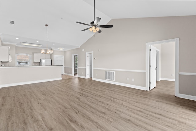 unfurnished living room featuring ceiling fan with notable chandelier, high vaulted ceiling, and light hardwood / wood-style flooring