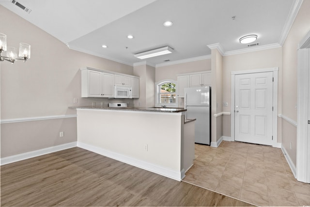 kitchen featuring white cabinets, crown molding, kitchen peninsula, and white appliances