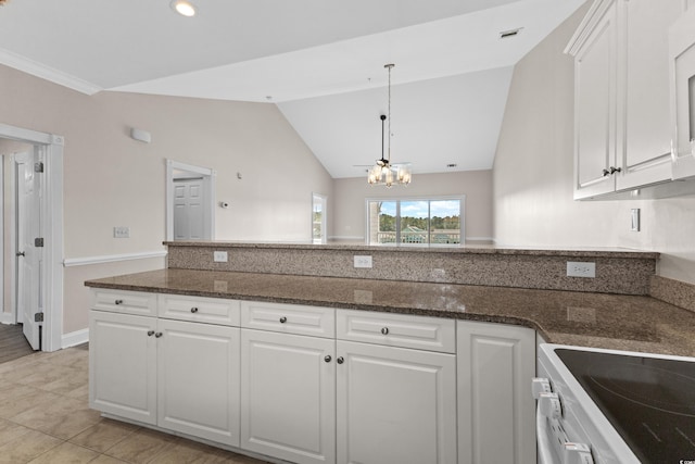 kitchen with dark stone counters, lofted ceiling, white cabinetry, and a chandelier