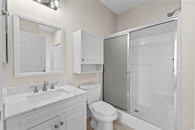 bathroom with a shower with door, toilet, vanity, and tile patterned floors