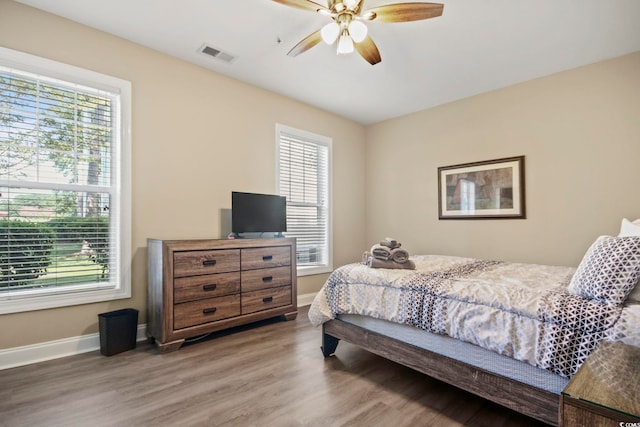 bedroom with multiple windows, ceiling fan, and hardwood / wood-style flooring