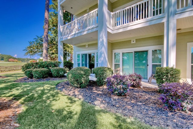 doorway to property with a balcony and a lawn