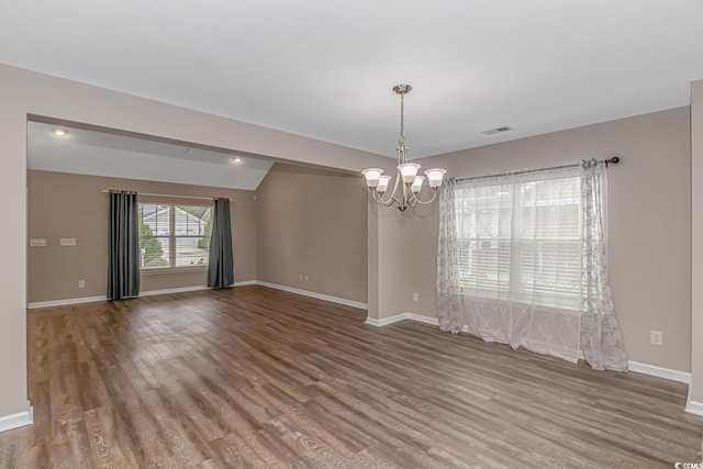 spare room with hardwood / wood-style floors and a notable chandelier